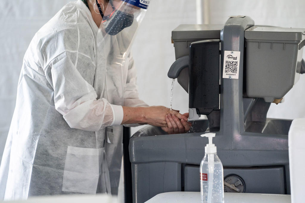 A COVID-19 screener washes their hands.